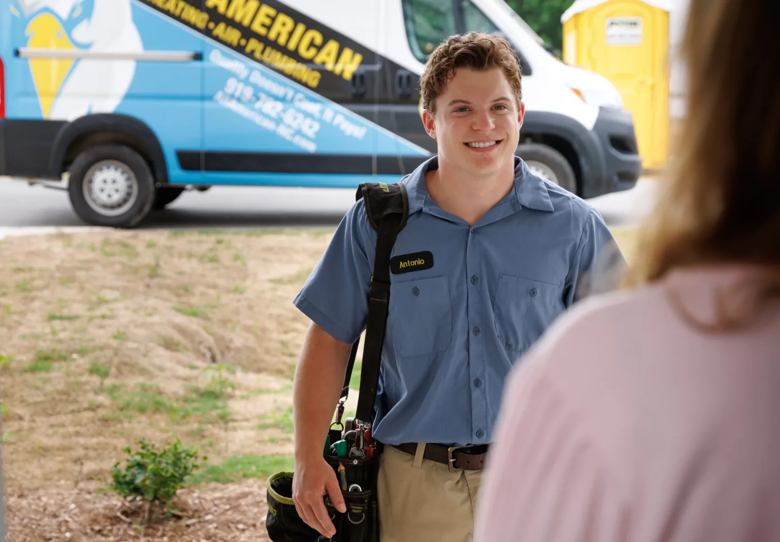All American Heating, Air & Plumbing technician assisting a customer in a home