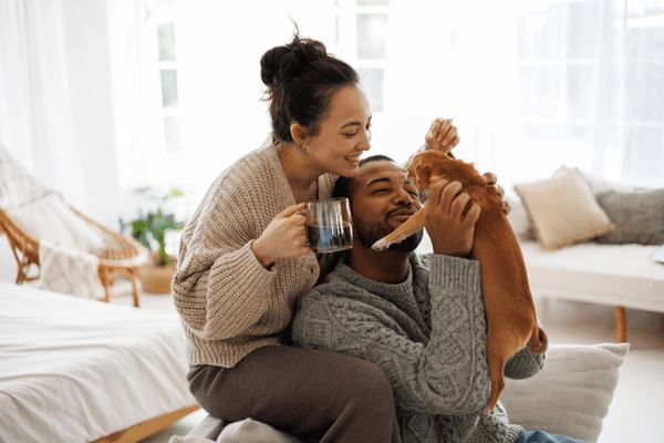 man and woman in living room holding up puppy