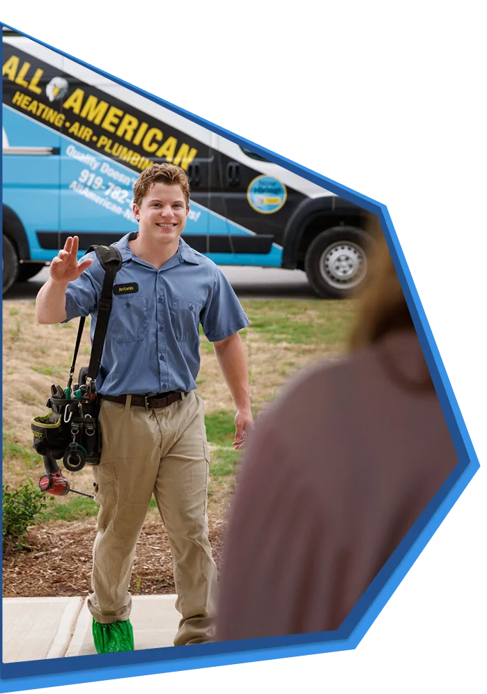 All American Heating, Air & Plumbing technician waving to a customer in front of a company van