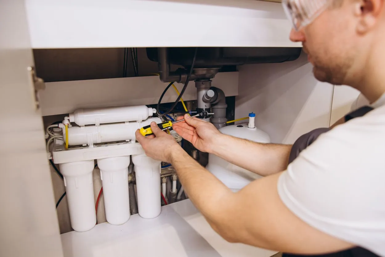 Plumber installing a water filter system under a kitchen sink